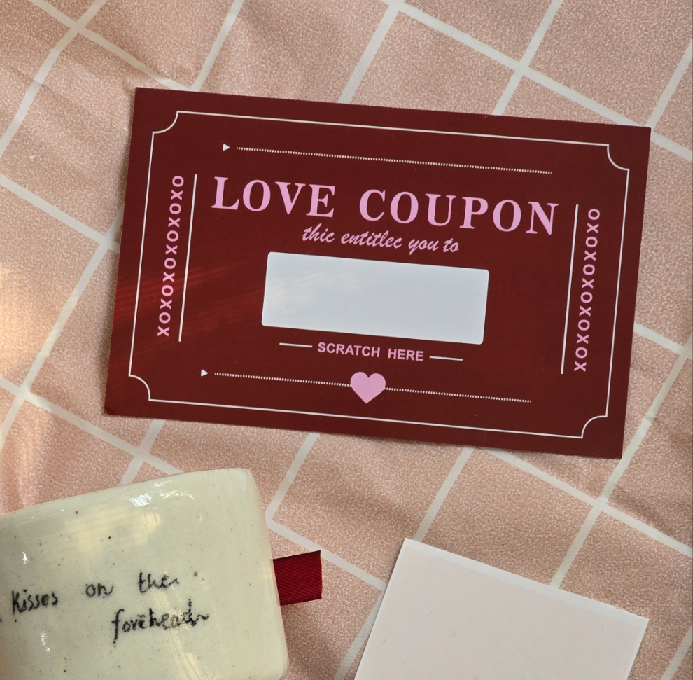 A red love coupon scratch card with a white scratch-off sticker, placed on a checkered background.