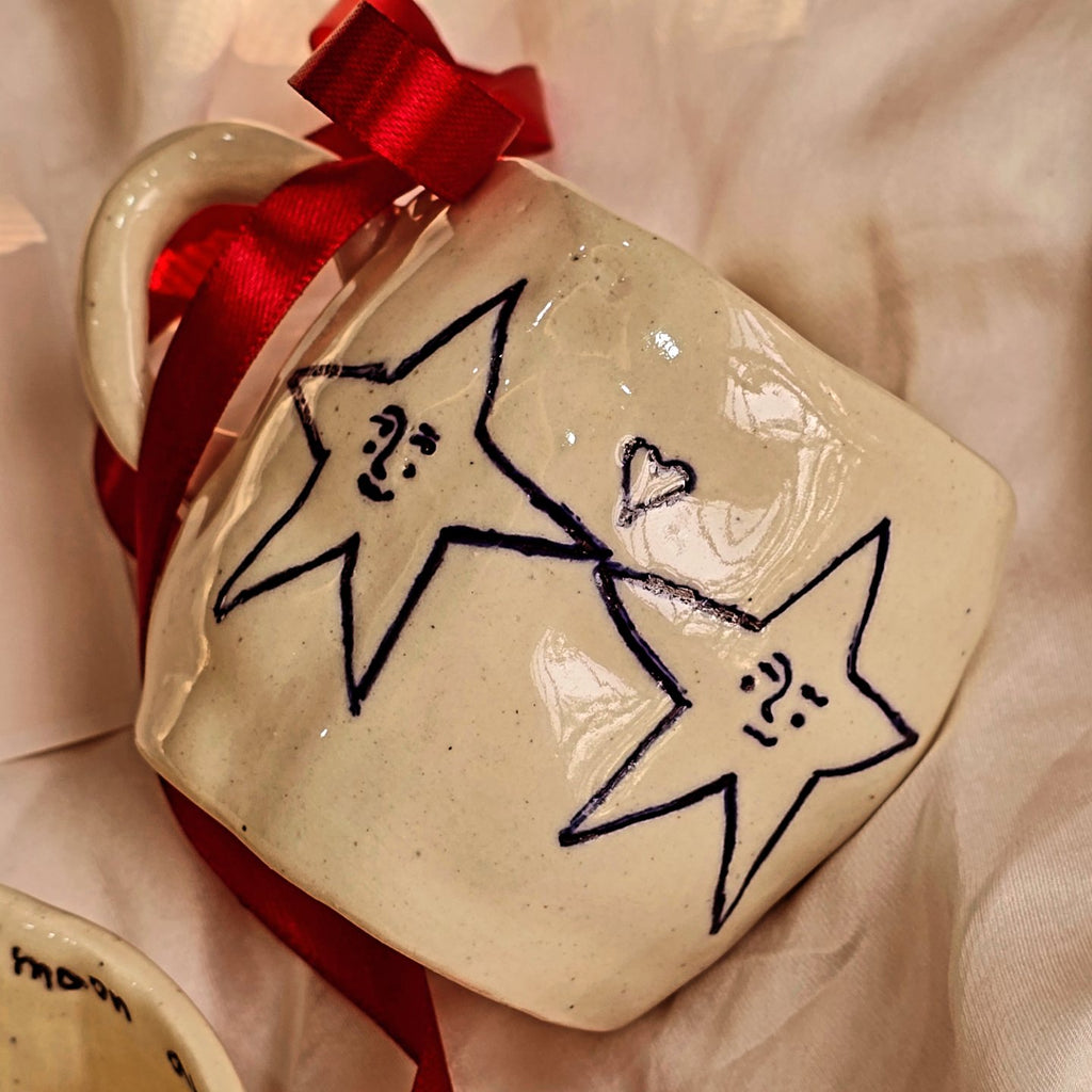 handmade valentines day ceramic mug by pastel jade ceramic studio with text love you to the moon and back and doodle of two stars holding hand in blue color  pastel jade in lahore pakistan all products are foodgrade and oven safe 